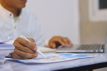 Middle-aged male manager sitting at desk in office with laptop, analyzing data, planning finances...