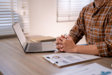 A man is sitting at a desk with a laptop and a clipboard