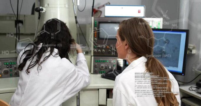 Instructor pointing, guiding researcher adjusting electron microscope settings for sample analysis