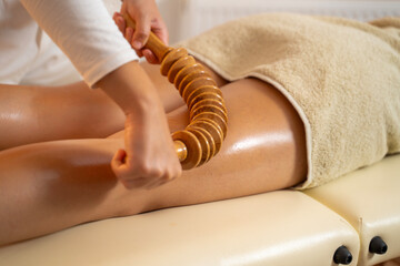 Maderotheraphy  anti cellulite massage with wooden tools, thigh massage closeup shot 