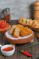 Close-up of delicious Indonesian fried snacks accompanied by a small bowl of red chili sauce and surrounded by red chilies