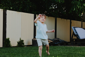 Joyful boy playing outdoors in a sunny garden, enjoying the summer atmosphere with vibrant greenery...