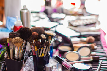 Makeup brushes and beauty products arranged on a table during bridal preparation. A colorful...