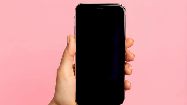 Hand holding blank screen mobile cell phone, isolated over light pink background for mockup, app presentation and advertising template