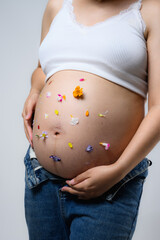 Beautiful pregnant woman hugging her tummy at home studio.