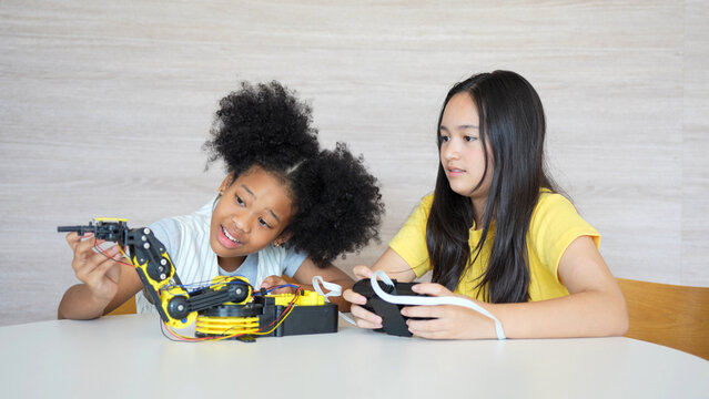 Diverse Kids Building a Robot Arm in a Science Workshop, Young Girls Engaged in Robotics and STEM Learning, Two Girls Exploring Technology and Innovation, Future Engineers