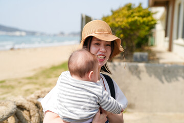In early March, a 6-month-old Japanese baby is held by a mother in her 30s on a sandy beach...