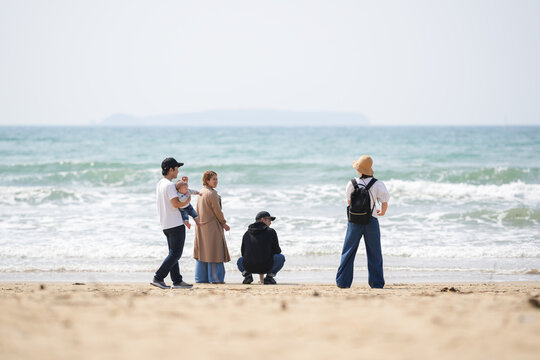 In early March, Japanese families enjoy the beach together: a 6-month-old baby, a 1-year-old girl, a 3-year-old girl, and parents in their 30s. A cheerful springtime scene filled with warmth and joy.