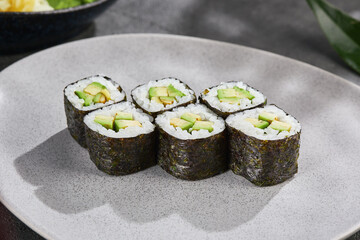 Avocado hosomaki rolls arranged on matte plate, bright lighting, overhead composition