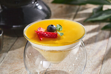 Mango panna cotta dessert with berries and mint, bright lighting, overhead rustic composition
