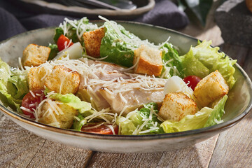 Chicken fillet caesar salad in bright natural lighting, rustic overhead composition