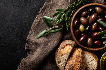 Overhead view of olives, olive oil, and fresh bread on linen