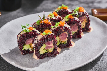 Wild rice maki sushi with tuna and avocado, bright overhead composition on a grey ceramic plate
