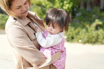 In early March, a Japanese mother in her 30s holds her 1-year-old daughter on a sandy beach by the sea. A heartwarming springtime moment filled with warmth and tenderness along the quiet shoreline.