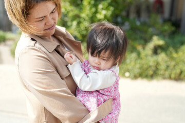 In early March, a Japanese mother in her 30s holds her 1-year-old daughter on a sandy beach by the sea. A heartwarming springtime moment filled with warmth and tenderness along the quiet shoreline.
