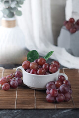 Fresh Red Grapes in a White Cup on a Wooden Mat