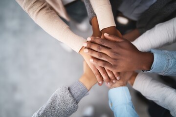 Coworkers joining hands in a huddle, representing their strong teamwork and collaboration, fostering unity and support among diverse colleagues