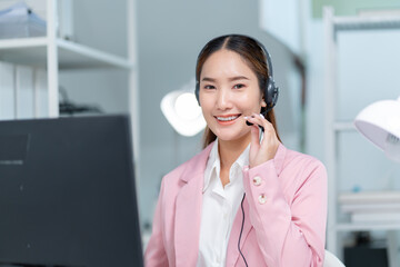 smiling Business woman or Asian female operator speaking with client via headset,computer and...