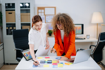 Two female designers brainstorming color palettes in a modern office. Creative teamwork, branding,...