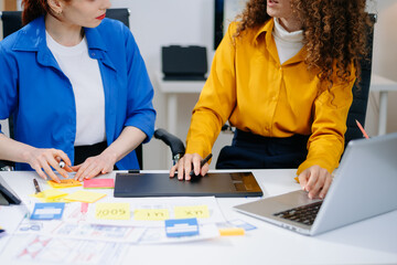Closeup of UX UI designers planning mobile layouts with wireframes, color swatches, sticky notes,...