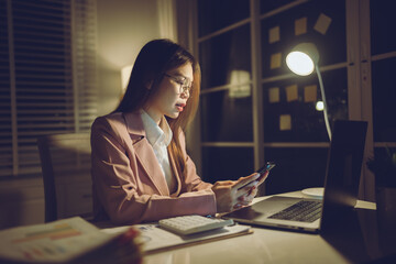 Professional young woman wearing glasses and blazer working with her laptop at a tidy desk,...
