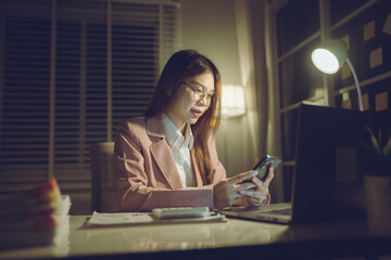 Professional young woman wearing glasses and blazer working with her laptop at a tidy desk,...