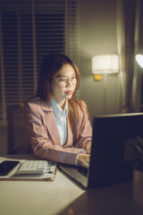 Professional young woman wearing glasses and blazer working with her laptop at a tidy desk,...