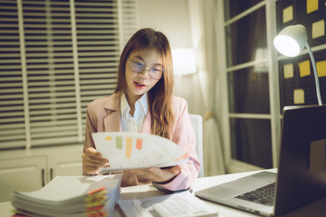 Professional young woman wearing glasses and blazer working with her laptop at a tidy desk,...