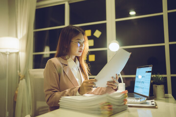 Professional young woman wearing glasses and blazer working with her laptop at a tidy desk,...