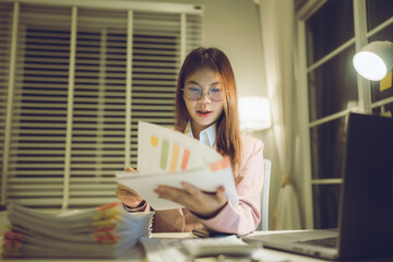 Professional young woman wearing glasses and blazer working with her laptop at a tidy desk,...
