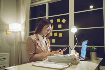Professional young woman wearing glasses and blazer working with her laptop at a tidy desk,...