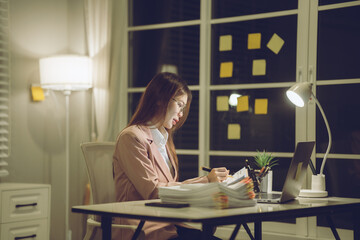 Professional young woman wearing glasses and blazer working with her laptop at a tidy desk,...