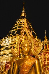 Fototapeta premium Golden Buddha statue illuminated at night in Wat Phra That Doi Suthep, Chiang Mai