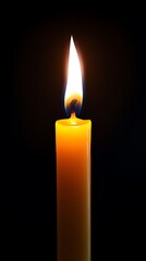 Yellow wax candle with bright flame burning in the dark background illuminates