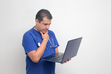 A dark-skinned Latino male specialist doctor uses a laptop to work on video call consultations, search for information, and study