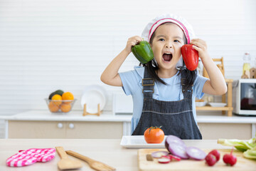 asian kid holding bell pepper and preparing vegetables meal in the kitchen