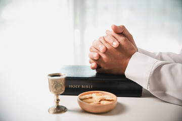During the holy communion ceremony in church, a hand is extended in faith to receive the sacred sacrament, reflecting the spiritual and religious worship central to Christianity.