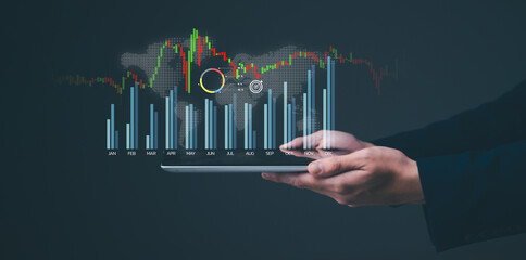 Hands holding a tablet displaying digital financial charts and graphs with a global map background.