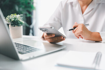 Close-up scene, a female seated at a table holds a smartphone, spending time on modern e-date services and social media through a mobile app, illustrating the wireless concept of digital usage.