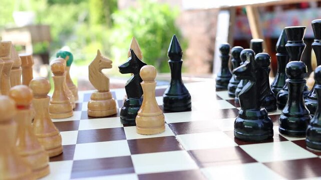 Close-up of person making a strategic move in chess, etaing white bishop on classic wooden board. Intellectual game concept, competition and planning. People playing chess.