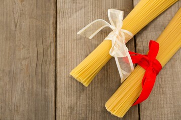 Raw spaghetti tied with ribbons on wooden table © vectorfusionart