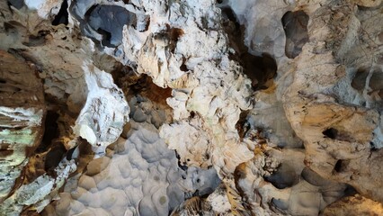 Inside Thien Cung Cave, Ha Long bay, Vietnam, showcasing dramatic stalactites and rugged limestone formations illuminated by soft lighting.