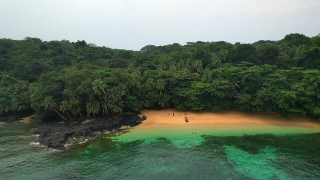 Aerial circular view of the Margarida beach with a boat anchored in the sand along with tourists at ilha do Principe (Prince Island) Sao Tome,Africa