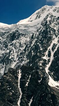 bird's eye view drone flight over snow-covered mountain peak stunning winter landscape aerial shot