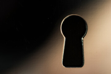 The image shows a close-up of a keyhole opening against a shiny metal surface, a classic keyhole...