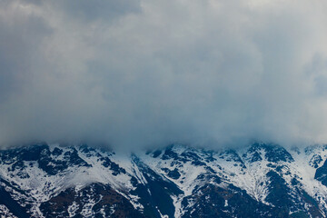 Dramatic snow-covered mountains partially obscured by clouds