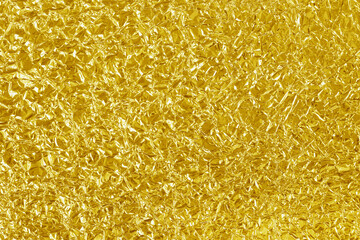Gold foil leaf shiny texture, abstract yellow wrapping paper for background and design art work.