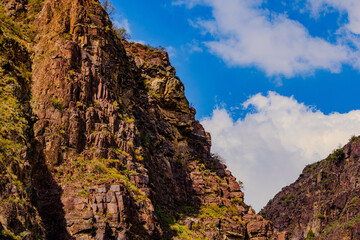 Dramatic sedimentary rock formations in mountainous region under blue sky