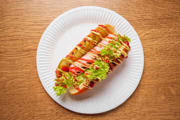 A delicious gourmet hot dog features vibrant vegetables and savory sauces, ready to be enjoyed