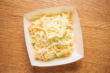 A vibrant bowl of coleslaw sits on a rustic wooden table, ready to complement any meal
